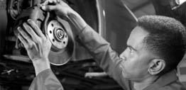 Black and white photo of a Barrington auto mechanic fixing brakes